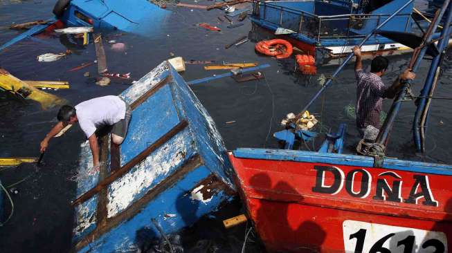 Nelayan memeriksa perahu yang rusak di pelabuhan Iquique, Chile, Rabu (2/4). [Reuters/Luis Hidalgo]