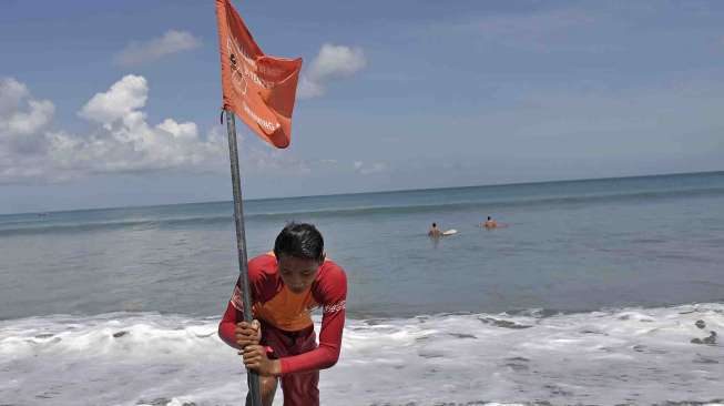 Petugas Badan Penyelamat Wisata Tirtha (Balawista) Kabupaten Badung memasang bendera rambu-rambu larangan berenang menyusul adanya seruan kewaspadaan dampak Tsunami Chili, di Pantai Kuta, Bali, Kamis (3/4). [Antara/Nyoman Budhiana]