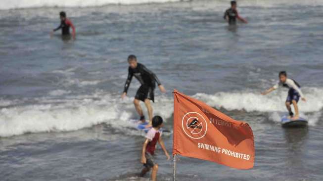 Petugas Badan Penyelamat Wisata Tirtha (Balawista) Kabupaten Badung memasang bendera rambu-rambu larangan berenang menyusul adanya seruan kewaspadaan dampak Tsunami Chili, di Pantai Kuta, Bali, Kamis (3/4). [Antara/Nyoman Budhiana]