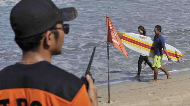 Petugas Badan Penyelamat Wisata Tirtha (Balawista) Kabupaten Badung memasang bendera rambu-rambu larangan berenang menyusul adanya seruan kewaspadaan dampak Tsunami Chili, di Pantai Kuta, Bali, Kamis (3/4). [Antara/Nyoman Budhiana]