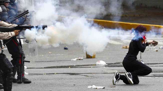 Polisi Venezuela menembakan gas air mata ke arah seorang demonstran di Caracas, Minggu (6/7). [Reuters/Carlos Garcia Rawlins]