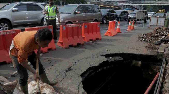 Jalan Jenderal Sudirman Amblas, Jakarta, Kamis (10/4). Jalan yang amblas tersebut mengakibatkan lubang yang besar berdiameter dua setengah meter dan dalam serta belum diketahui penyebabnya. [suara.com/Bernard Chaniago]