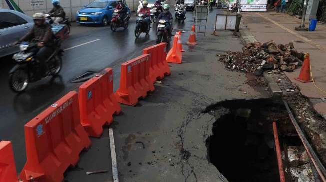 Jalan Jenderal Sudirman Amblas, Jakarta, Kamis (10/4). Jalan yang amblas tersebut mengakibatkan lubang yang besar berdiameter dua setengah meter dan dalam serta belum diketahui penyebabnya. [suara.com/Bernard Chaniago]