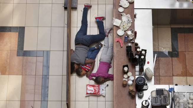 Seorang perempuan dan seorang anak bersembunyi saat insiden penyerangan Westgate Mall di Nairobi, Kenya (21/9/2013). Foto ini bagian dari foto pemenang Pulitzer 2014 untuk kategori Breaking News Photography (Reuters/Tyler Hicks)