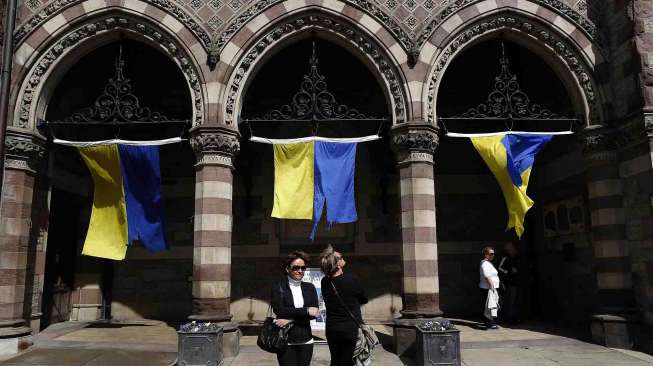 Pejalan kaki melihat spanduk di depan gereja di lokasi lomba lari maraton di Boylston Street, Boston, Massachusetts, Senin (14/4). [Reuters/Dominick Reuter] 