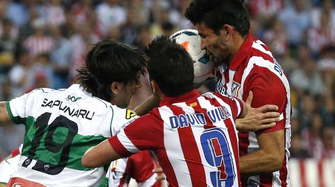 Pemain Atletico Madrid David Villa dan Diego Costa berebut bola dengan pemain Elche Cristian Sapunaru dalam laga La Liga di Vicente Calderon, Sabtu (19/4). (Reuters/Juan Medina)