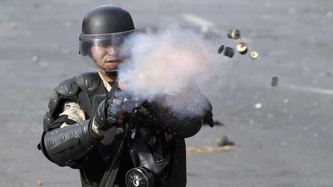 Polisi menembakan gas air mata ke arah demonstran di Caracas, Senin (21/4). [Reuters/Christian Veron] 