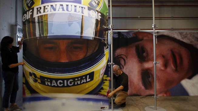 Pekerja memasang foto Ayrton Senna, di sirkuit Imola, Italia, Rabu (30/4). [Reuters/Alessandro Garofalo]