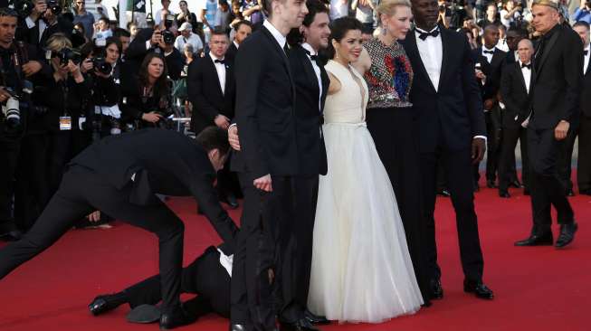 Seorang lelaki mencoba menyusup ke bawah gaun artis America Ferrera, saat ia berpose di karpet merah Festival Film Cannes untuk menghadiri pemutaran film \"How to Train Your Dragon 2\", Jumat (16/5/2014) (Reuters/Benoit Tessier)