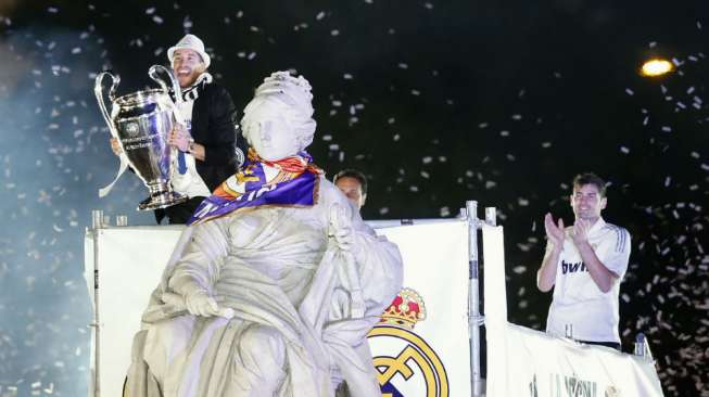 Sergio Ramos (kiri) memegang trofi Liga Champions dan kapten Real Madrid (kanan) merayakan keberhasilan mereka dan berpesta di Cibeles Square, Madrid. (Reuters/Andrea Comas)