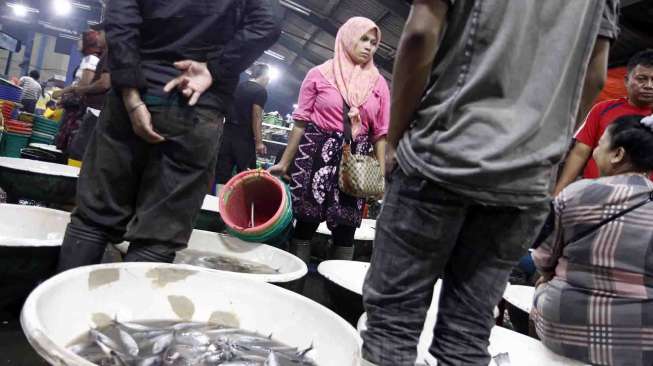 Ratih, seorang pengepulkan memilih ikan di  Muara Angke, Jakarta untuk dijual kembali secara eceran di Pasar Anyar Tangerang. [suara.com/Adrian Mahakam]