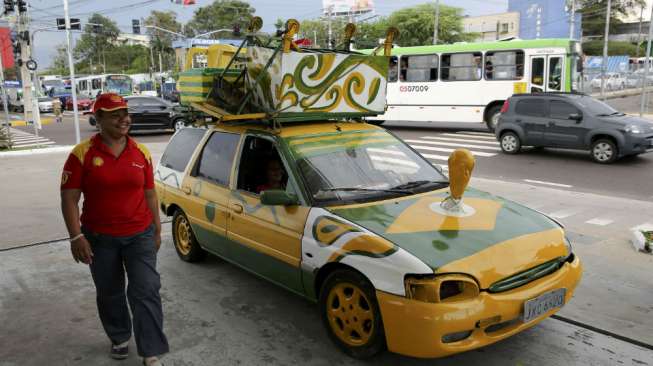 Mobil dengan aksesoris replika trofi Piala Dunia dengan dekorasi bendera Brasil di jalanan kota Manaus. (Reuters/Siphiwe Sibeko) 