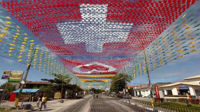 Bendera Swiss (depan) dan bendera peserta Piala Dunia lainnya dipasang di atas sebuah jalan di Santa Cruz Cabralia, Brazil, Rabu (11/6). [Reuters/Arnd Wiegmann] 