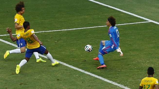 Penjaga gawang Meksiko, Guillermmo Ochoa, berhasil menghadang serangan dua pemain Brasil, Rabu (18/6) [Reuters/Mike Blake].