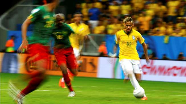 Neymar menggiring bola di hadapan para pemain Kamerun, dalam laga Senin (23/6/2014). [Reuters/Dominic Ebenbichler]