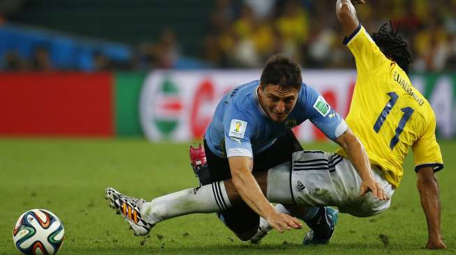 Pemain Uruguay Diego Lugano (kiri) dijatuhkan Juan Cuardado [Reuters/Kai Pfaffenbach]