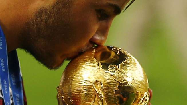 Mario Goetze mencium trofi Piala Dunaia usai mengalahkan Argentina dalam Final Piala Dunia 2014 di stadion Maracana Stadium di Rio de Janeiro, Brazil, Minggu (13/7). [Reuters/Damir Sagolj] 