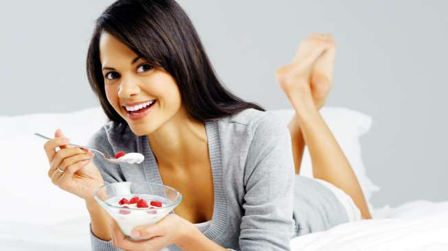 Ilustrasi mengonsumsi yogurt, salah satu makanan yang mengandung probiotik. (Sumber: Shutterstock)
