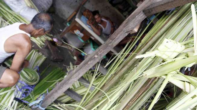 Penjual janur bungkus ketupat di jalan Palmerah Raya Jakarta, Senin (21/7). [suara.com/Adrian Mahakam]