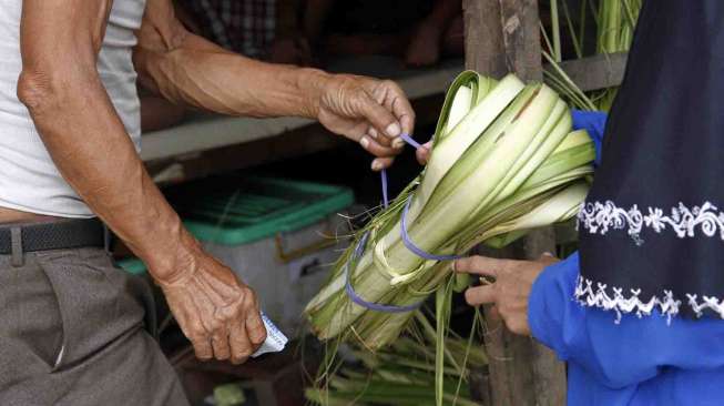 Penjual janur bungkus ketupat di jalan Palmerah Raya Jakarta, Senin (21/7). [suara.com/Adrian Mahakam]