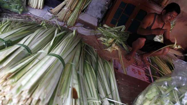 Penjual janur bungkus ketupat di jalan Palmerah Raya Jakarta, Senin (21/7). [suara.com/Adrian Mahakam]