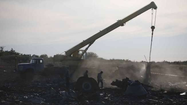 Petugas memindahkan reruntuhan pesawat Malaysia MH17 di desa Hrabove, Donetsk, Ukraina, Minggu (20/7). [Reuters/Maxim Zmeyev]