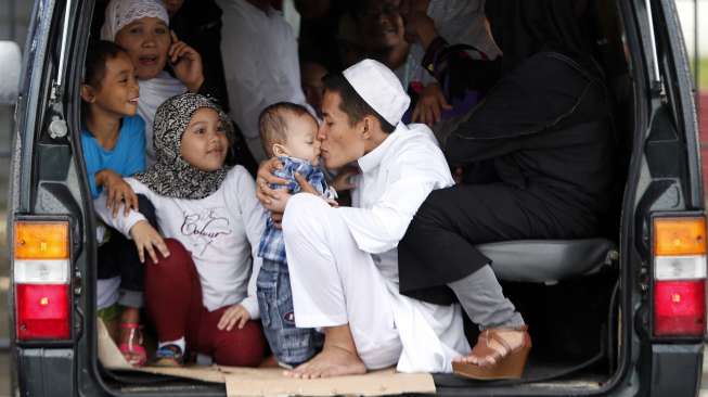 Seorang ayah mencium anaknya sesaat sebelum dilaksanakannya sholat Idul Fitri di Manila, Filipina. (28/7). (Reuters/Erik De Castro)