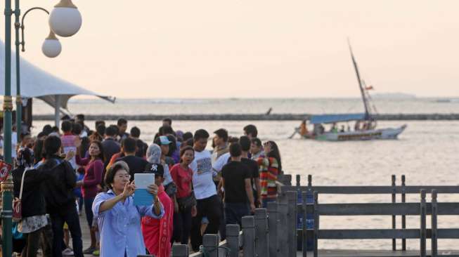 Pengunjung memadati tempat wisata pantai Ancol Jakarta, Senin (28/7). [suara.com/Kurniawan Mas'ud]