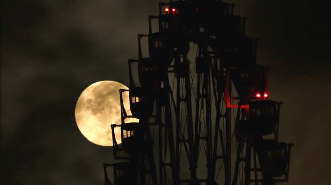 Sebuah penampakan \"supermoon\" dengan latar depan sebuah \"ferris wheel\" di Tokyo, Jepang, Senin (11/8/2014) dini hari. [Reuters/Toru Hanai]