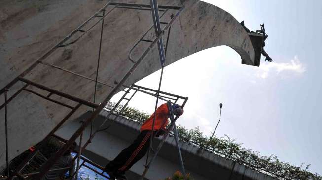 Balai Konservasi Jakarta memasang spanduk penutup di dasar patung Dirgantara atau patung Pancoran Jakarta, Rabu (13/8). [suara.com/Adrian Mahakam]