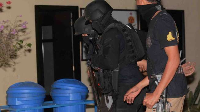 Polisi menggelandang salah seorang dari tujuh terduga anggota Islam State Iraq and Syiria (ISIS) di Kantor Polda Sulawesi Tengah di Palu, Sabtu (13/9). [Antara/Basri Marzuki]