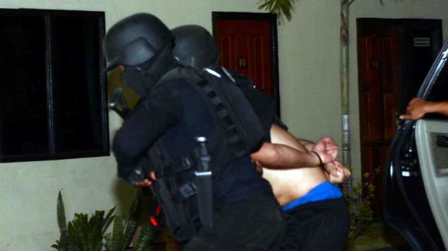 Polisi menggelandang salah seorang dari tujuh terduga anggota Islam State Iraq and Syiria (ISIS) di Kantor Polda Sulawesi Tengah di Palu, Sabtu (13/9). [Antara/Basri Marzuki]