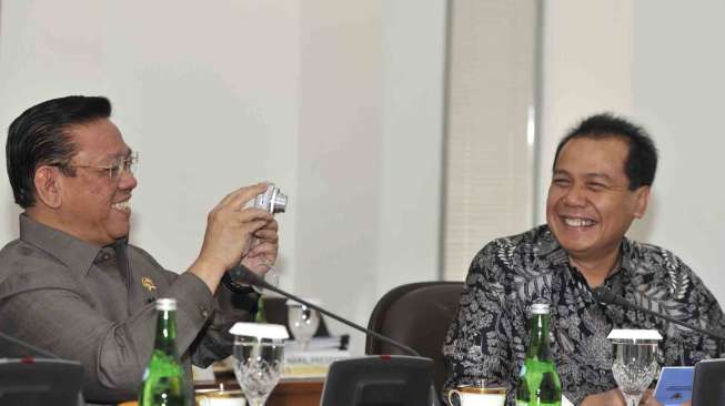 Menko Kesra Agung Laksono (kiri) memotret koleganya disaksikan Menko Perekonomian Chairul Tanjung (kanan) sebelum rapat terbatas kabinet bidang polhukam yang membahas perkembangan RUU Pilkada di Kantor Presiden, Rabu (17/9). [Antara/Andika Wahyu]