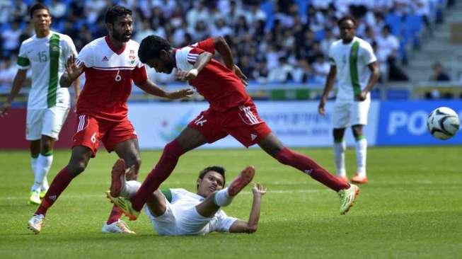 Pesepak bola Indonesia AFandi Eko Utomo (bawah) terjatuh setelah diganjal pesepak bola Maladewa Mohamed Irufaan (kanan) pada penyisihan grup E Asian Games 2014 di Incheon, Korsel, Kamis (18/9). [Antara/Saptono]