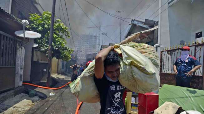Warga menyelamatkan diri dan harta bendanya dari lokasi kebakaran di pemukiman warga kawasan Cipinang Besar Utara, Jatinegara, Jakarta Timur, Rabu (24/9). [Antara/Widodo S. Jusuf]