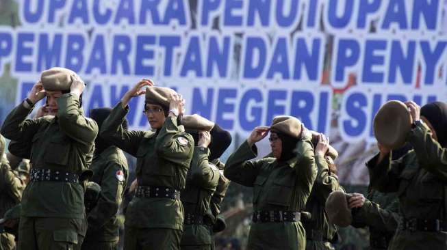 Peserta pendidikan bela negara memasang baret ketika  pembaretan dan pemasangan brevet pada  upacara penutupan pendidikan pendahuluan bela negara di Kawasan  Monas Jakarta, Kamis (25/9). [Antara/Wahyu Putro A]