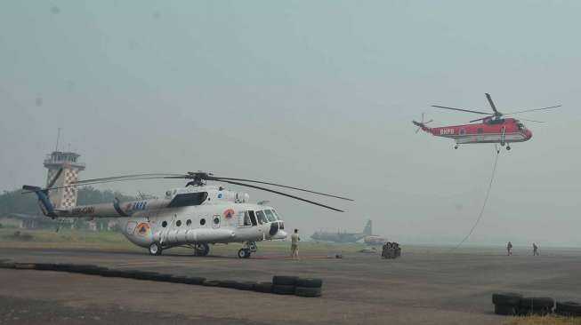 Helikopter milik BNPB yang bertugas melakukan penyiraman titik api terhenti kegiatannya sementara akibat menebalnya kabut asap di  Bandara Sultan Mahmud Badaruddin II Palembang, Sumsel, Jumat (26/9).[Antara/Feny Selly]   