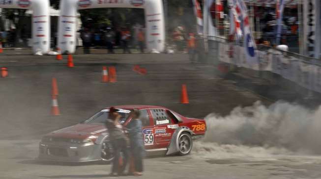 Aksi para pebalap beradu tandem di lintasan kembar dengan handicap slalom dalam ajang kompetisi \"IIMS Gymkhana Race War 2014\" di Loading Bay Hall D Indonesia International Motor Show 2014 Jakarta, Sabtu (26/9). [suara.com/Kurniawan Mas'ud]