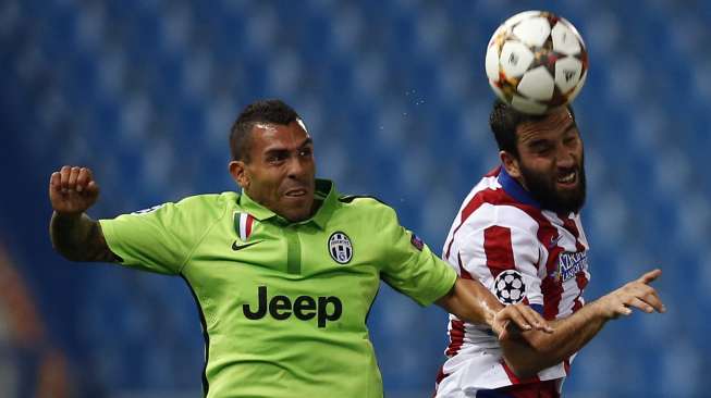 Pemain Juventus Carlos Tevez (kiri) dan pemain Atletico Madrid Arda Turan bertarung berebut bola. (REUTERS/Sergio Perez)