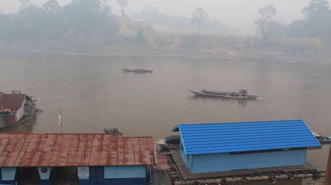 Perahu bermotor berlayar di pedalaman Sungai Barito wilayah Muara Teweh Kabupaten Barito Utara, Kalimantan Tengah yang tertutup kabut asap tebal, Senin (6/10). [Antara/Kasriadi]