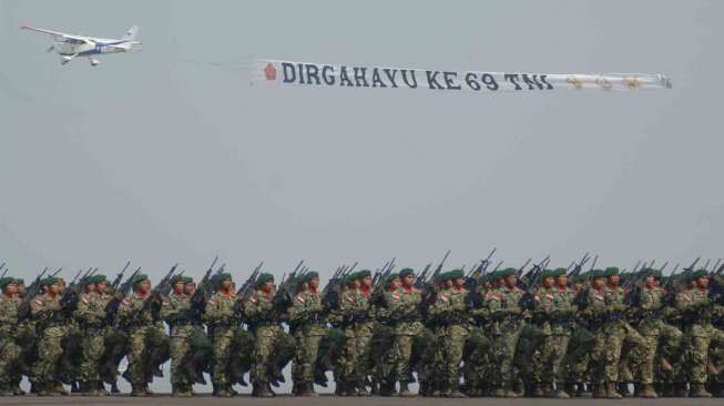 Sebuah pesawat cessna melintas diatas prajurit TNI AD disela-sela upacara peringatan HUT ke-69 TNI di Dermaga Ujung, Koarmatim, Surabaya, Jatim, Selasa (7/10). [Antara/Suryanto]