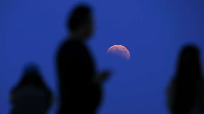 Fase awal terjadinya gerhana bulan yang disebut dengan \"bulan darah\" disaksikan dari Lapangan Tenis Qizhong, Shanghai, Cina. (Reuters/Aly Song)