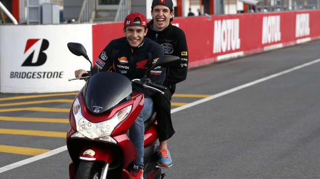 Pebalap tim Repsol Honda, Marc Marquez (depan), mencoba naik skuter di Sirkuit Motegi, Jepang, Kamis (9/10/2014), bersama adiknya yang membalap di kelas Moto3, Alex Marquez. [Reuters/Toru Hanai]