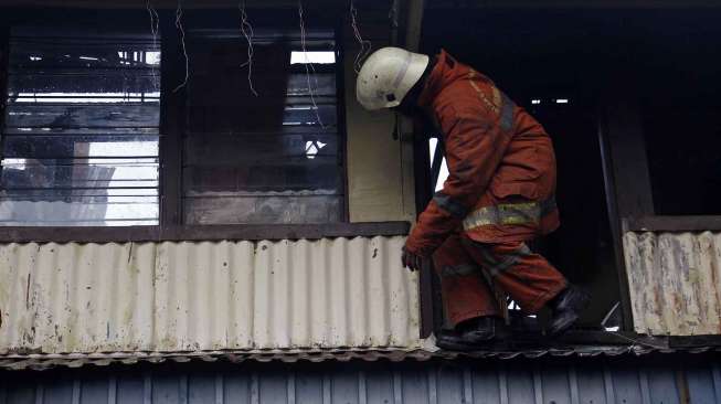 Petugas pemadam kebakaran dibantu warga berusaha memadamkan api yang membakar perumahan padat penduduk di Asrama TNI AD Berlan, Jakarta, Selasa (14/10). [suara.com/Kurniawan Mas'ud]