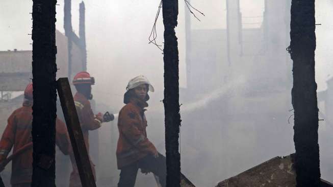 Petugas pemadam kebakaran dibantu warga berusaha memadamkan api yang membakar perumahan padat penduduk di Asrama TNI AD Berlan, Jakarta, Selasa (14/10). [suara.com/Kurniawan Mas'ud]