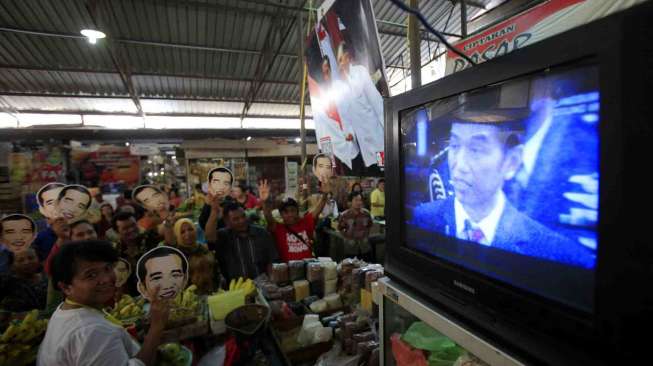 Sejumlah pedagang dan pengunjung menonton bersama melalui TV acara pelantikan Presiden, Joko Widodo dan wakilnya, Jusuf Kalla di Pasar Gede, Solo, Jawa Tengah, Senin (20/10). 