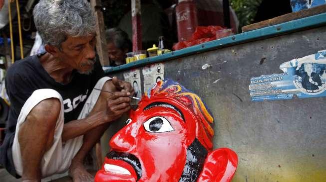 Salah seorang pekerja tengah merampungkan wajah boneka onde-ondel di sanggarnya di Jakarta Pusat, Selasa (4/11). [suara.com/Kurniawan Mas'ud]