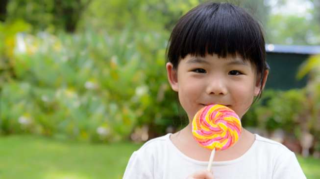 Ilustrasi anak makan permen lolipop. (Shutterstock)