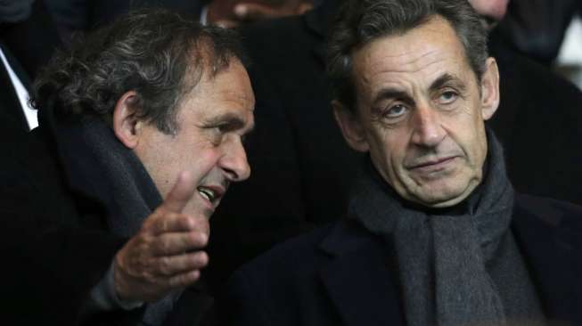 Presiden UEFA Michel Platini (kiri) dan mantan Presiden Prancis Nicolas Sarkozy berbincang saat menyaksikan laga antara PSG vs Chelsea (18/2)[Reuters/Christian Hartmann]