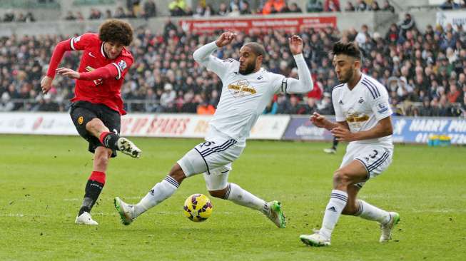 Pemain Manchester United Marouane Fellaini mencoba melepaskan tendangan namun dibayangi dua pemain Swansea City. Reuters / Matthew Childs Livepic